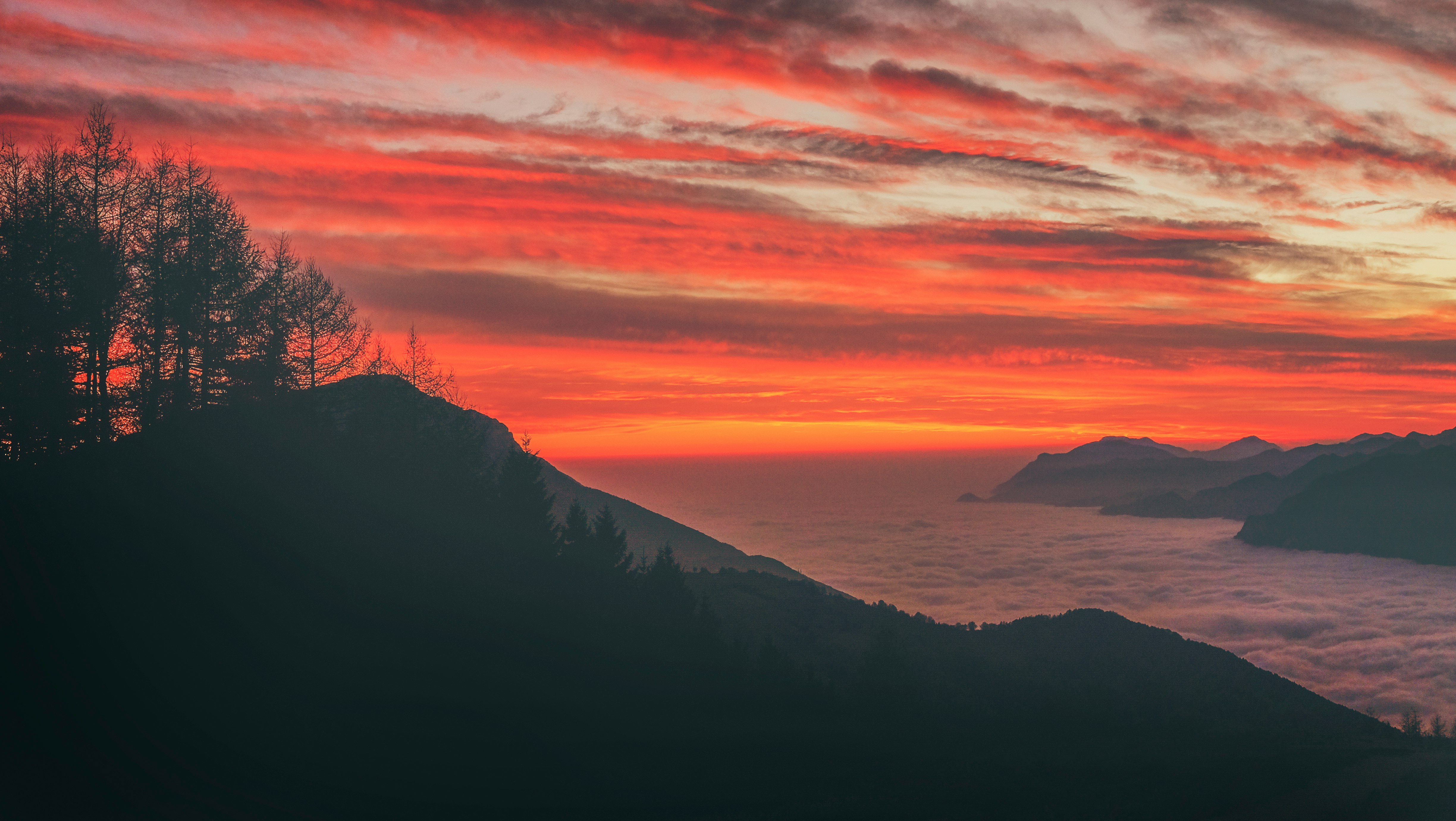 silhouette photo of mountain near body of water during sunset